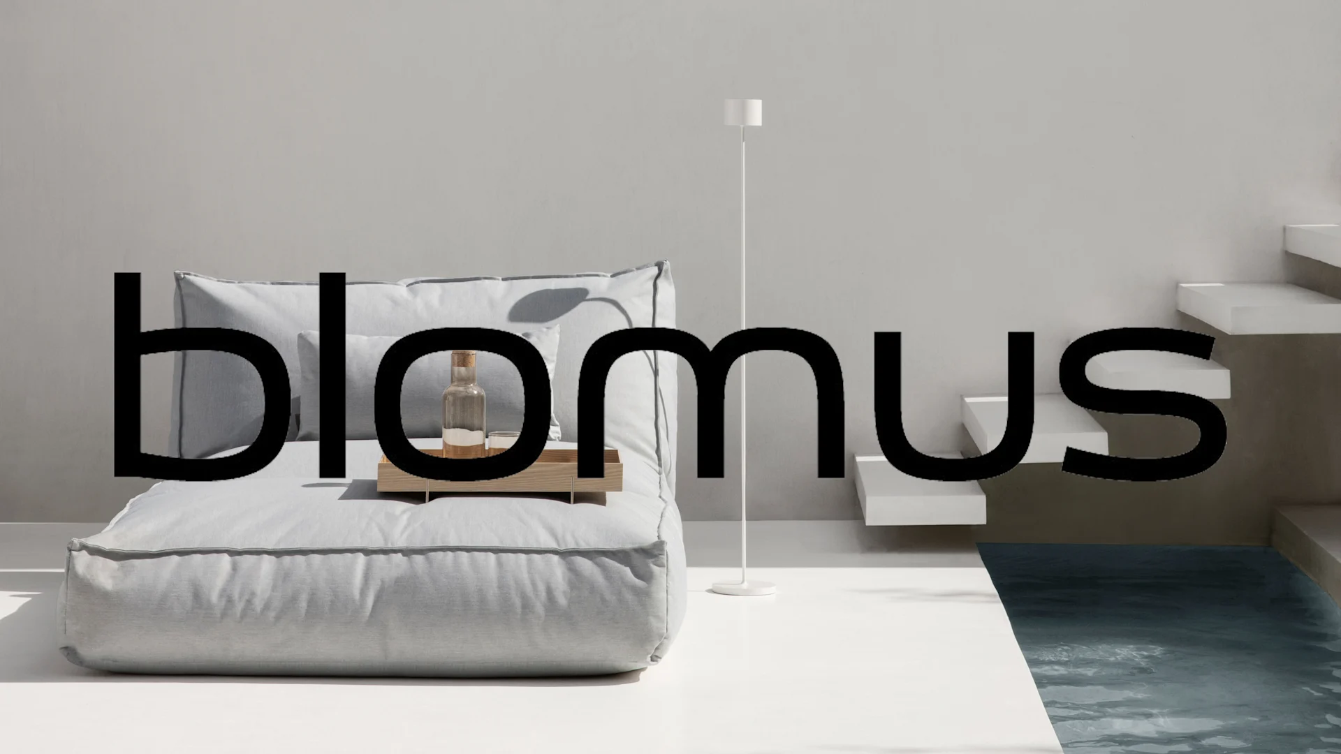 blomus-logotyp över en ljusgrå utomhussoffa med dynor, en vit golvlampa och en liten pool med trappor.