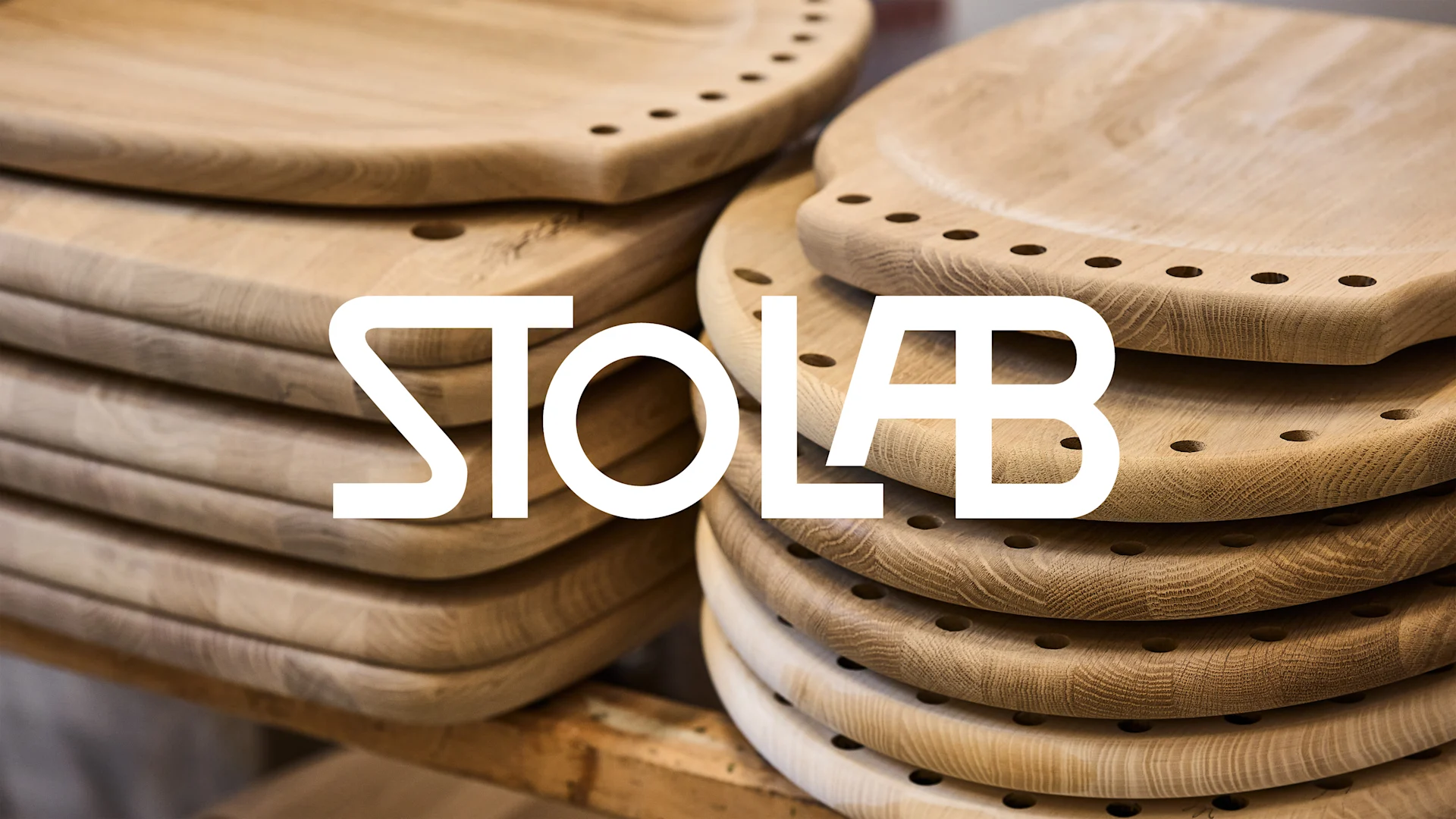 Staplar av obehandlade trästolsitsar med hål, med texten STOLAB över.
