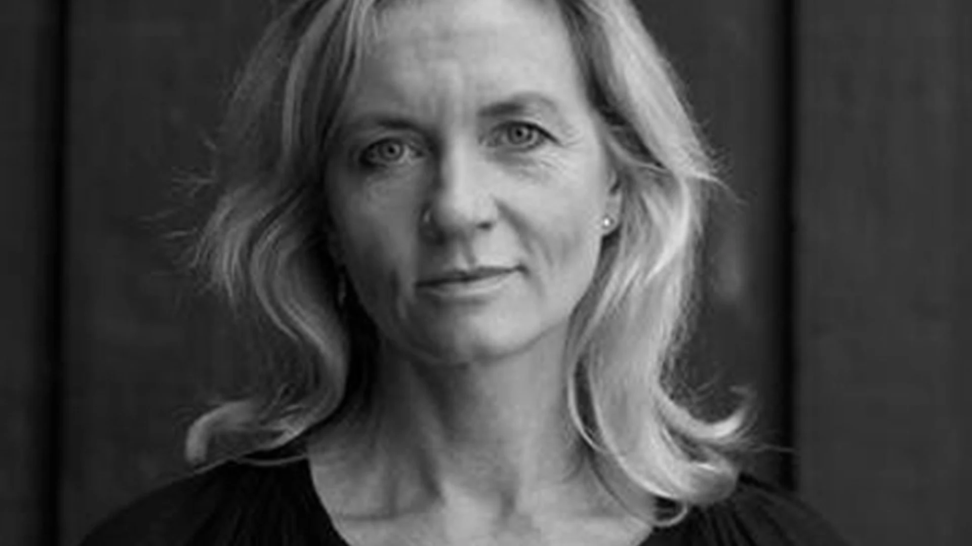 Svartvitt porträtt av en blond kvinna med neutralt ansiktsuttryck.