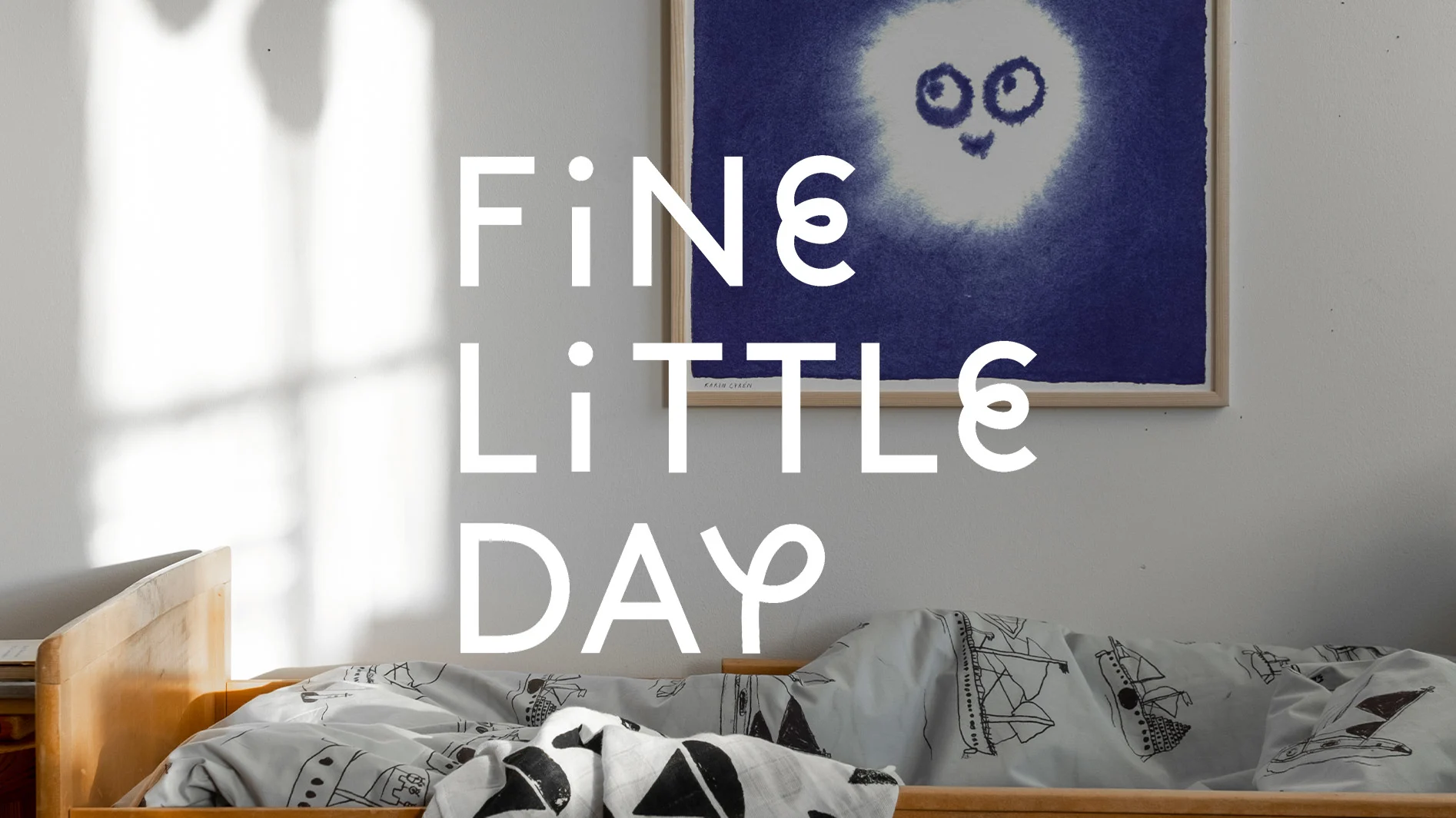 Barnsäng med mönstrade sängkläder och bild av ett leende ansikte. Text: 'FiNe LiTTLe DAY'.